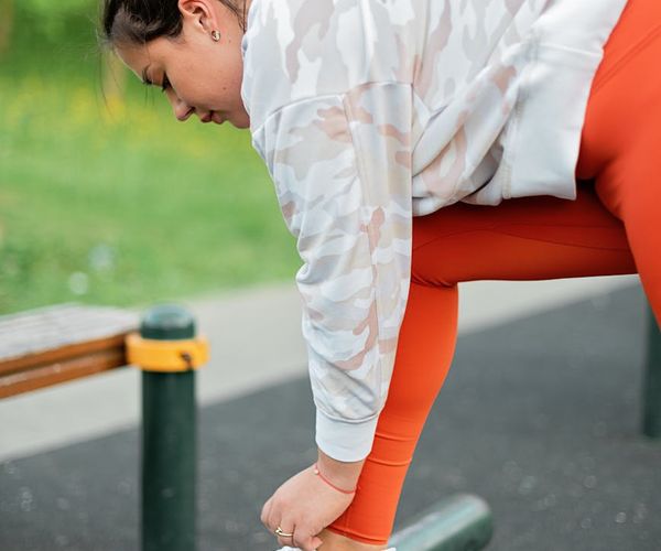 A person tying their shoelaces, preparing for a daily walk or light exercise.